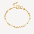 Gold bracelet on a beige surface with dried flowers