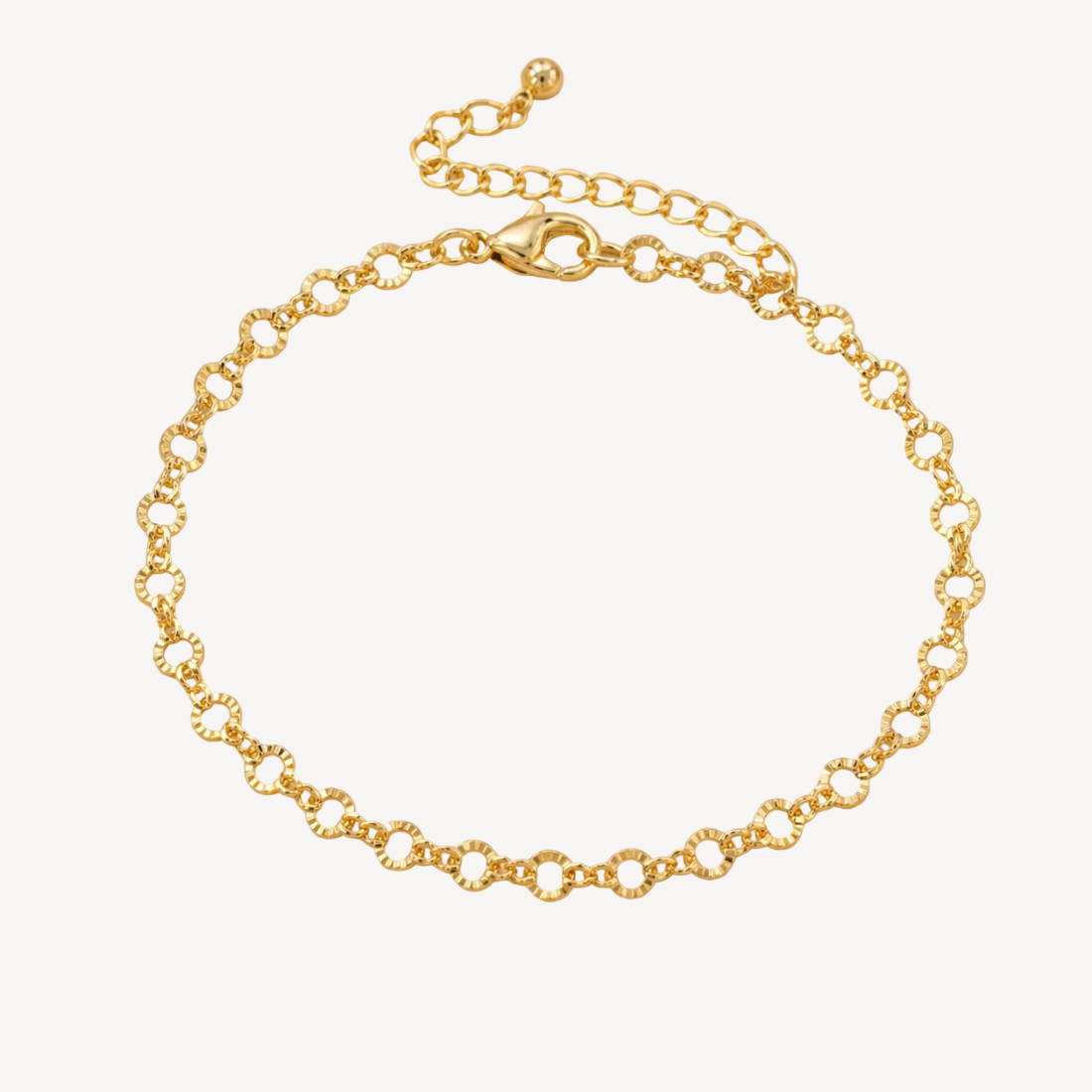 Gold bracelet on a beige surface with dried flowers