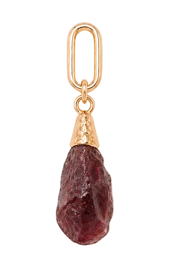 Gold pendant with a purple gemstone on a beige background
