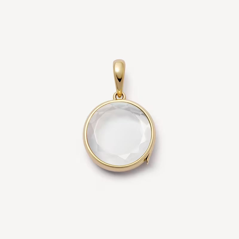 Gold pendant with a clear stone on a white background