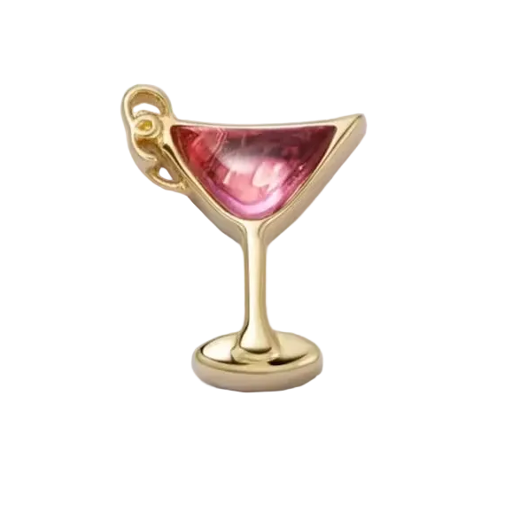 Gold charm shaped like a cocktail glass with a pink gem on a white background