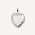 Heart-shaped pendant with gold frame and clear stone on a white background