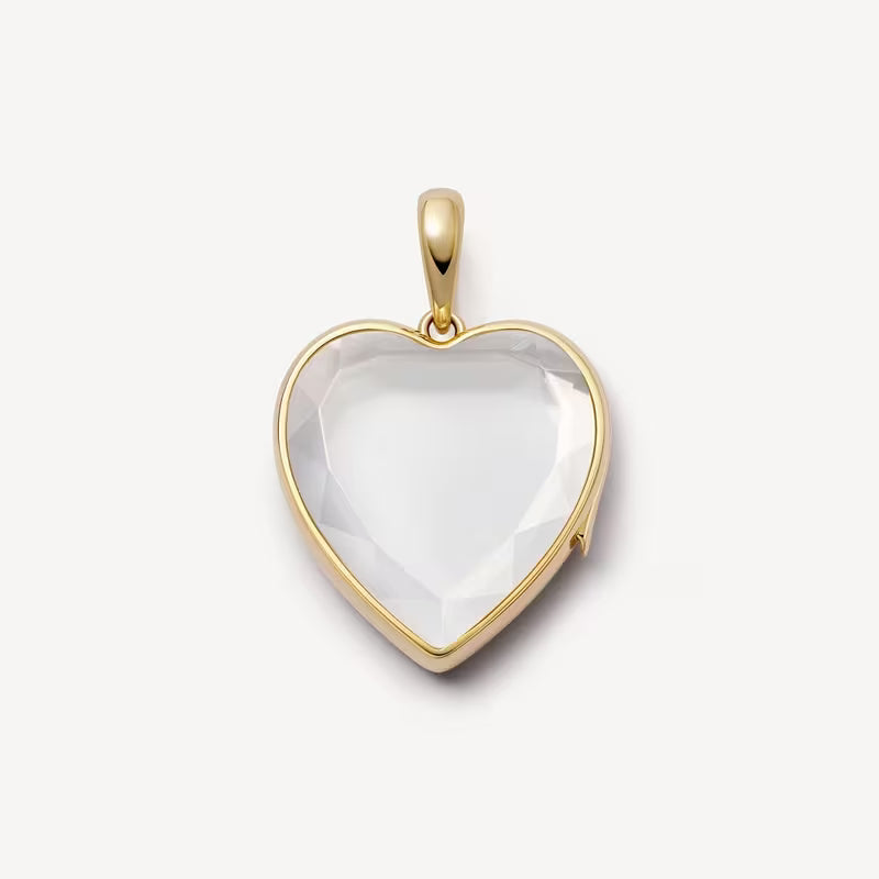 Heart-shaped pendant with gold frame and clear stone on a white background