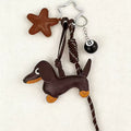 Dog-shaped keychain with star, leash, and ball on a white background