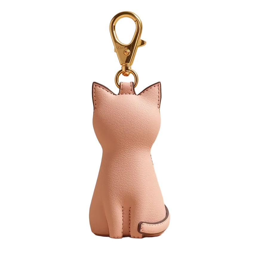 Pink cat-shaped keychain on a beige background