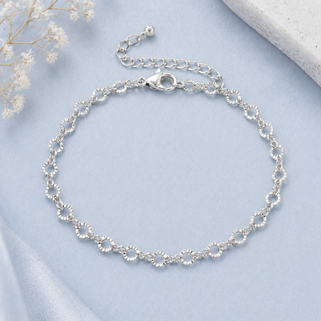 Silver bracelet on a light blue fabric background with white flowers.